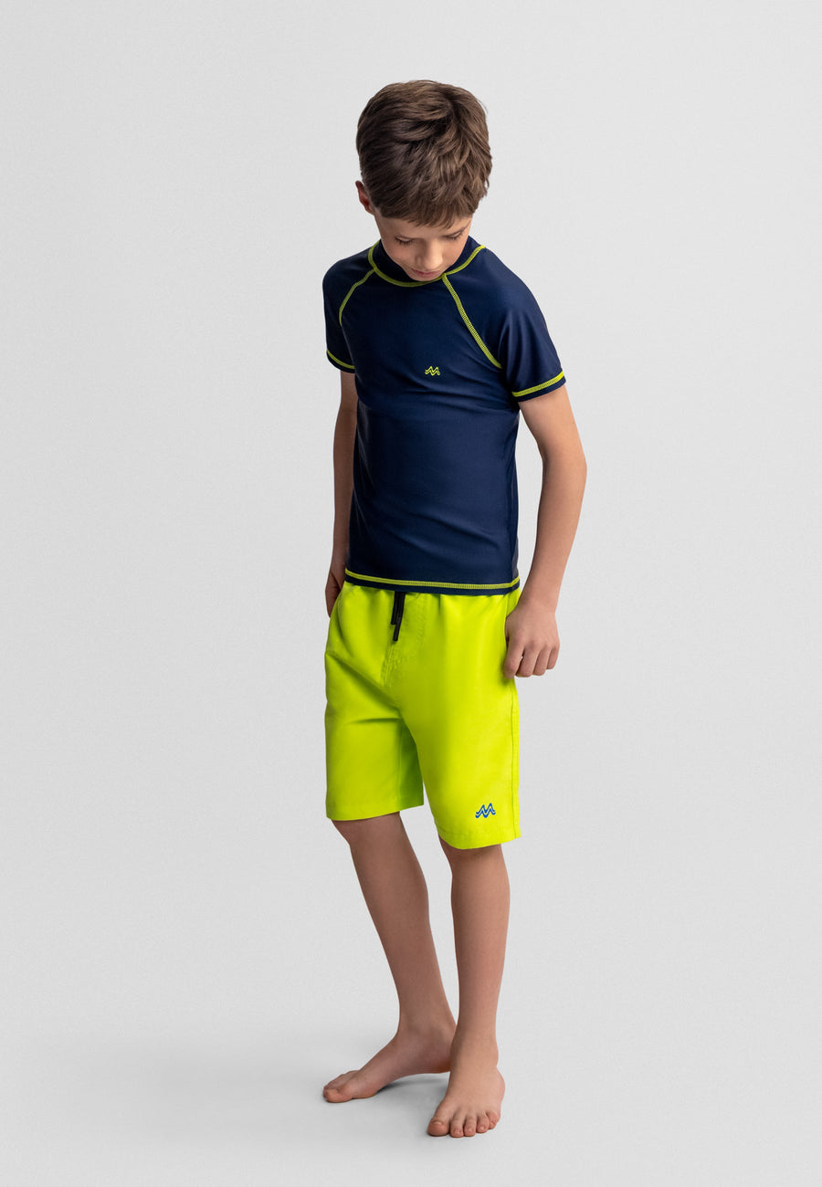 Child wearing a navy and green shirt with matching shorts on a light gray background