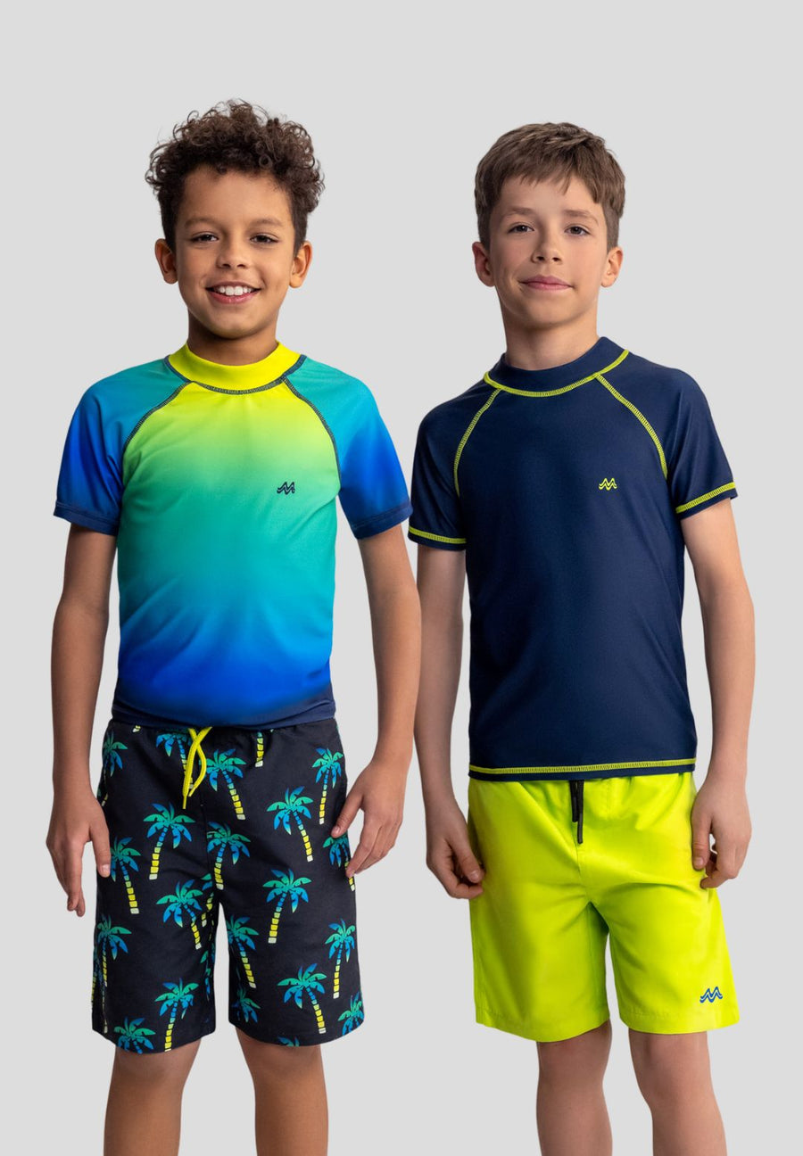 Two children wearing colorful swim shirts and shorts on a plain background