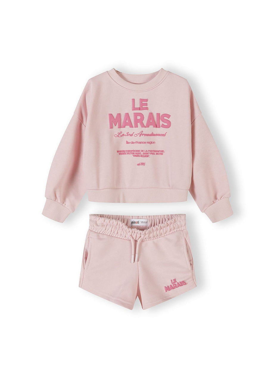 Light pink sweatshirt and shorts set laid flat on white background, showing French-inspired 'Le Marais' text print on sweatshirt front