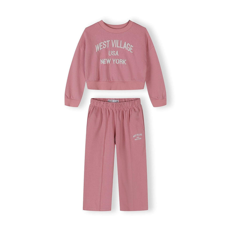 Pink tracksuit set with cropped sweatshirt and wide-leg joggers featuring West Village USA New York text, displayed on white background